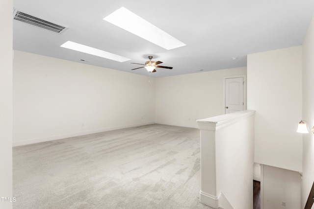 unfurnished living room with visible vents, light colored carpet, a skylight, and baseboards