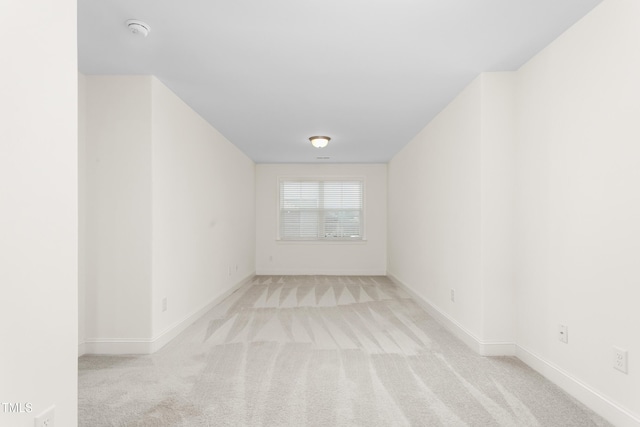 spare room featuring carpet flooring and baseboards