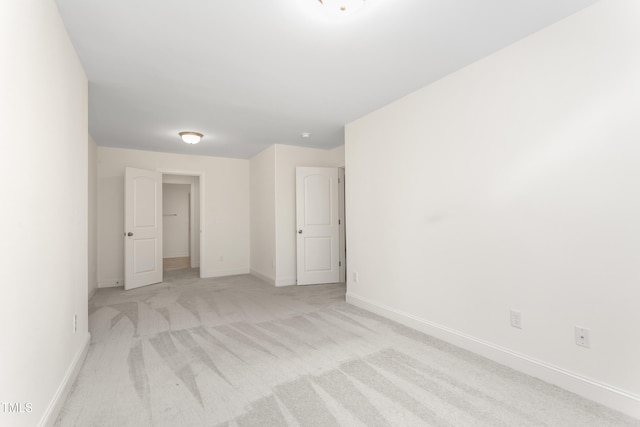 unfurnished room with light colored carpet and baseboards