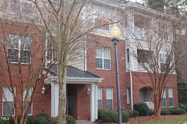 view of property with metal roof, brick siding, and a standing seam roof