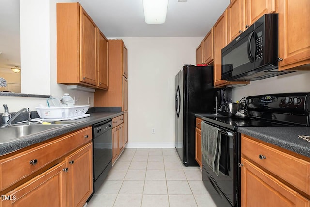 kitchen with dark countertops, black appliances, a sink, and light tile patterned flooring