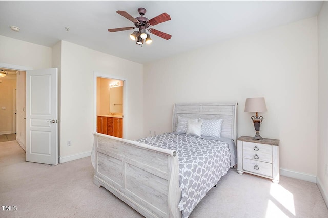 bedroom featuring baseboards, ensuite bathroom, a ceiling fan, and light colored carpet