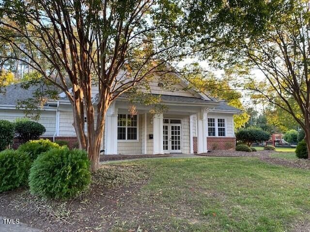 view of front of house featuring french doors, brick siding, and a front lawn