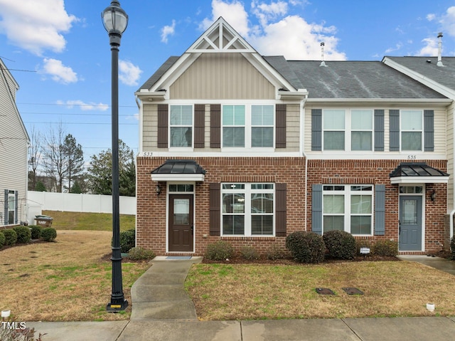 townhome / multi-family property featuring a front yard, brick siding, and fence