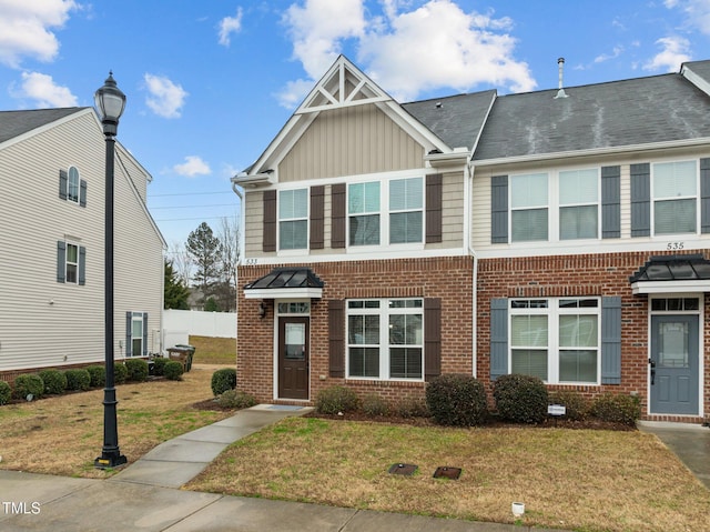 multi unit property with brick siding, board and batten siding, and a front yard