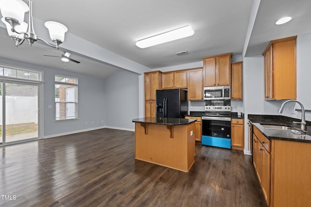 kitchen with dark wood-style floors, a kitchen bar, stainless steel appliances, and a sink