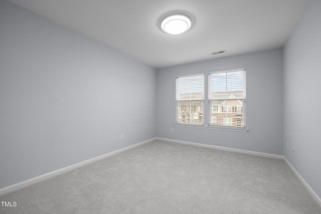 unfurnished room with carpet, visible vents, and baseboards