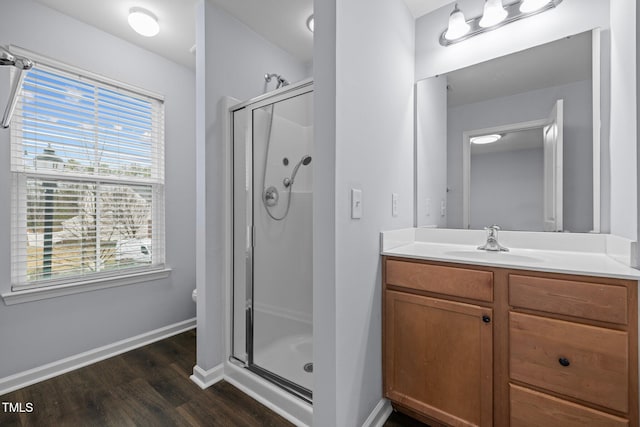 full bathroom featuring a stall shower, wood finished floors, vanity, and baseboards