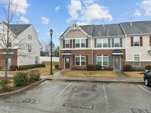 townhome / multi-family property with uncovered parking, brick siding, and board and batten siding