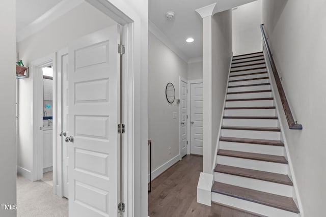 staircase with wood finished floors, baseboards, ornamental molding, and recessed lighting