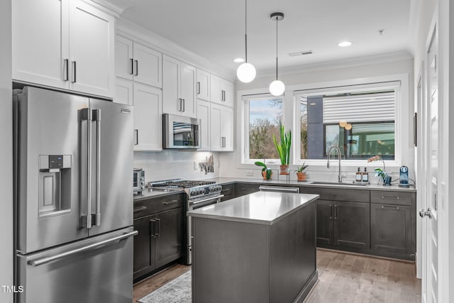 kitchen with tasteful backsplash, visible vents, light wood-style flooring, high end appliances, and a sink