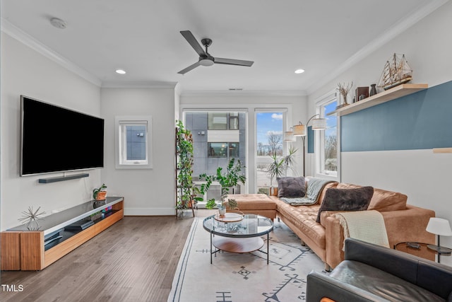 living area featuring crown molding, wood finished floors, baseboards, and ceiling fan