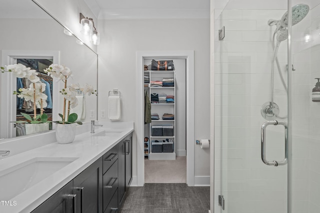 full bathroom with double vanity, a spacious closet, a stall shower, and a sink