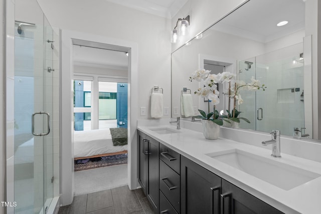 bathroom with crown molding, double vanity, a stall shower, and a sink