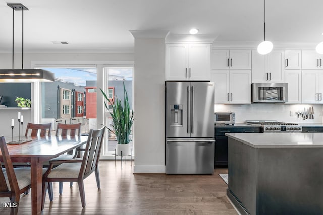 kitchen featuring stainless steel appliances, backsplash, wood finished floors, and white cabinetry