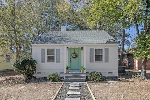 bungalow-style home with a shingled roof, crawl space, and a chimney