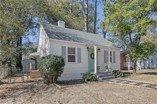 bungalow-style house featuring crawl space, a chimney, fence, and roof with shingles