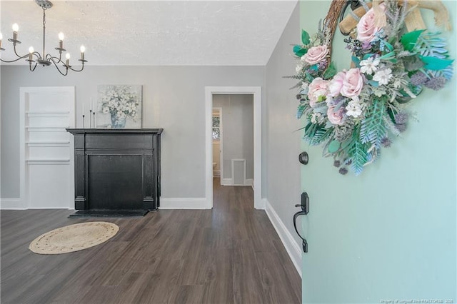 interior space featuring dark wood-style floors, a chandelier, a textured ceiling, and baseboards