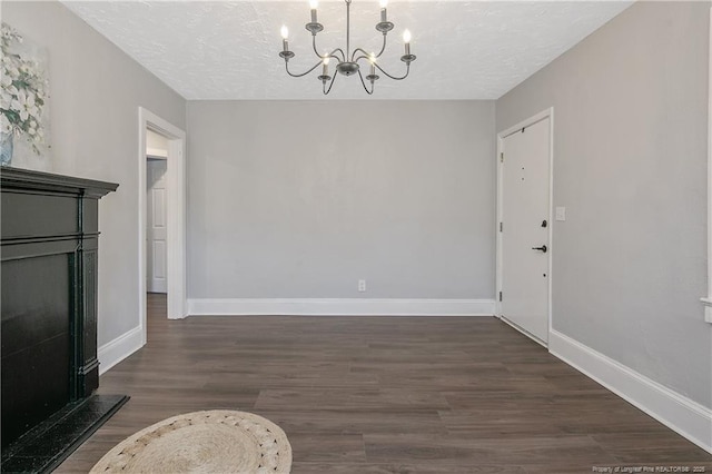 dining room with dark wood-style floors, a fireplace, an inviting chandelier, a textured ceiling, and baseboards