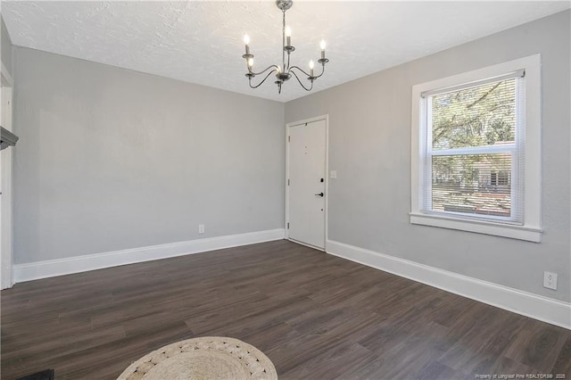 interior space featuring dark wood-style floors, a textured ceiling, baseboards, and an inviting chandelier