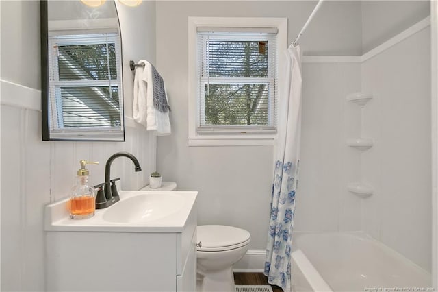 full bath featuring wood finished floors, shower / tub combo, vanity, and toilet