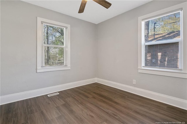 spare room with visible vents, baseboards, dark wood-type flooring, and a wealth of natural light