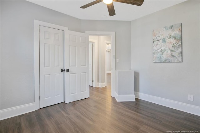 unfurnished bedroom with dark wood-type flooring, a closet, baseboards, and a ceiling fan