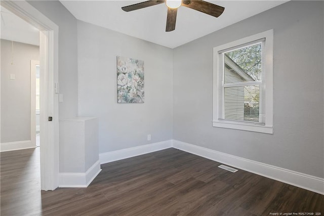 empty room featuring a ceiling fan, baseboards, visible vents, and dark wood-type flooring