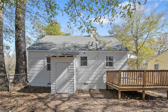 rear view of house featuring a shingled roof, fence, and a wooden deck