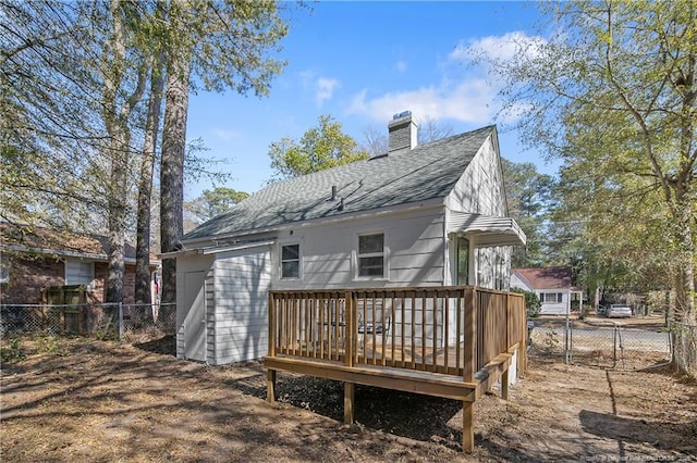 back of house featuring a chimney, fence, a deck, and roof with shingles