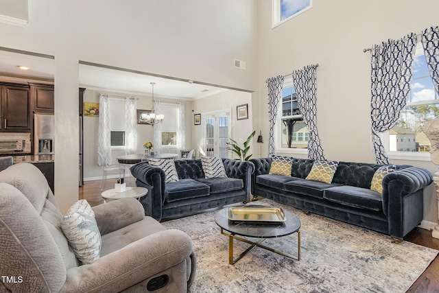 living area featuring a toaster, visible vents, wood finished floors, an inviting chandelier, and a high ceiling