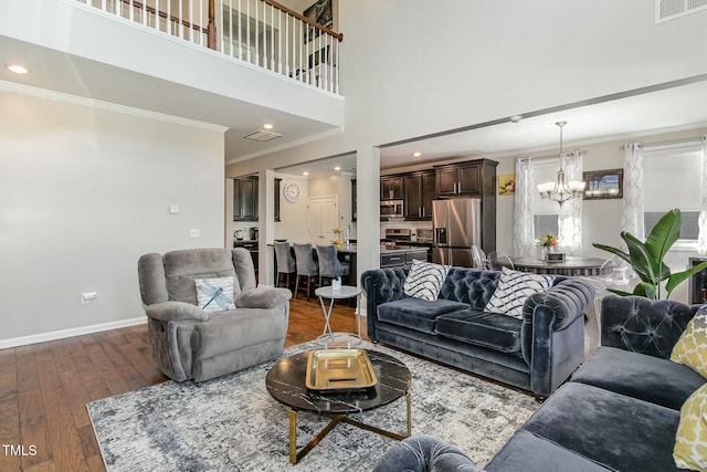 living area with visible vents, dark wood-type flooring, ornamental molding, a chandelier, and baseboards