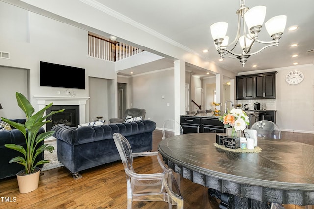 dining room featuring crown molding, visible vents, a glass covered fireplace, wood finished floors, and baseboards