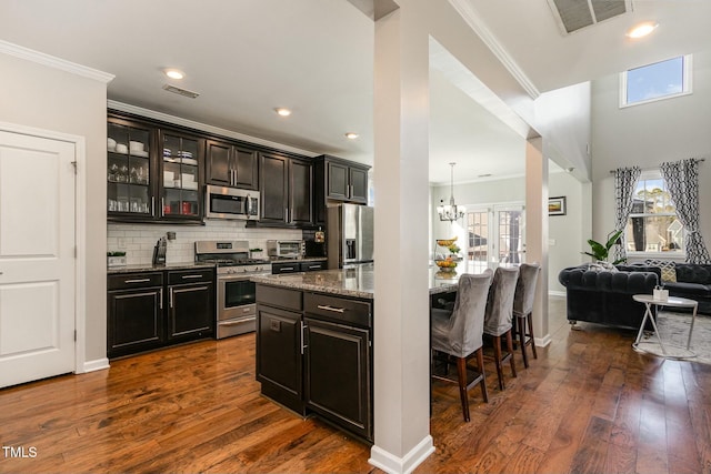 kitchen with appliances with stainless steel finishes, visible vents, crown molding, and tasteful backsplash