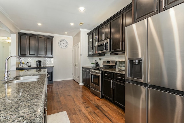 kitchen with stainless steel appliances, dark wood-type flooring, dark stone countertops, and a sink