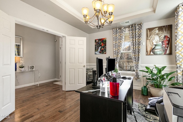 office space featuring a notable chandelier, a raised ceiling, visible vents, ornamental molding, and wood finished floors