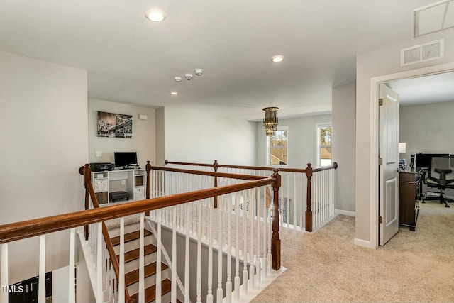 hallway with light carpet, an upstairs landing, visible vents, and recessed lighting