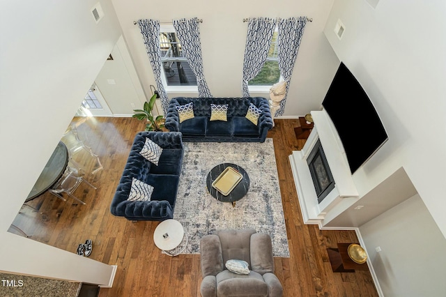 living room with baseboards, visible vents, and wood finished floors