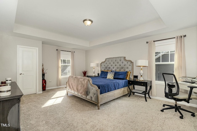 bedroom featuring a tray ceiling, carpet flooring, and baseboards