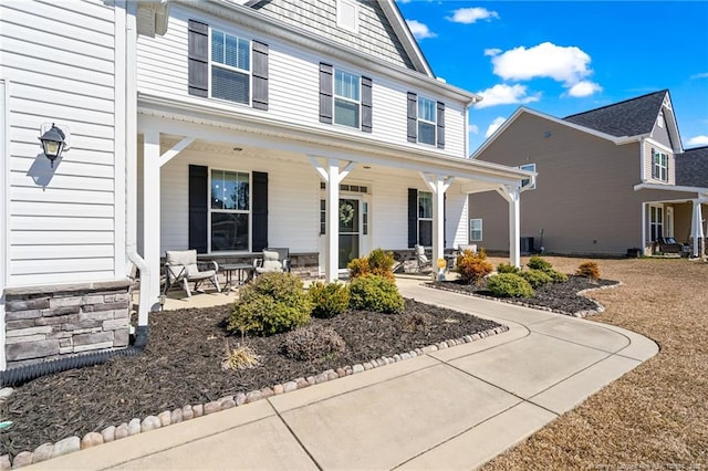 view of front of home with stone siding, covered porch, and central AC