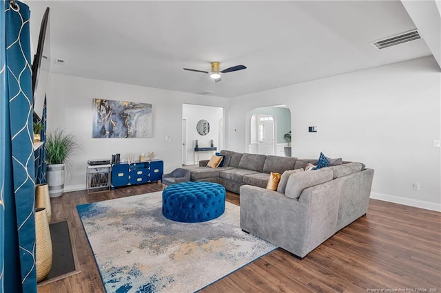 living area featuring arched walkways, wood finished floors, and visible vents