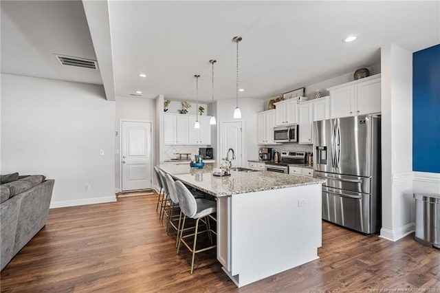 kitchen with dark wood-style floors, a kitchen bar, stainless steel appliances, and a sink