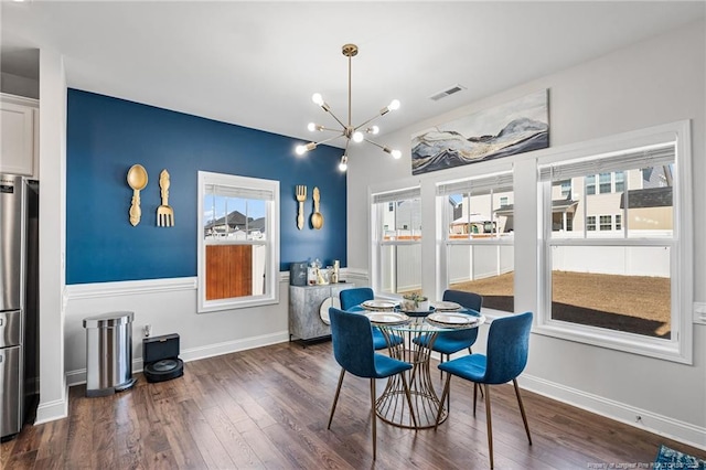 dining room with dark wood-type flooring, a chandelier, visible vents, and baseboards