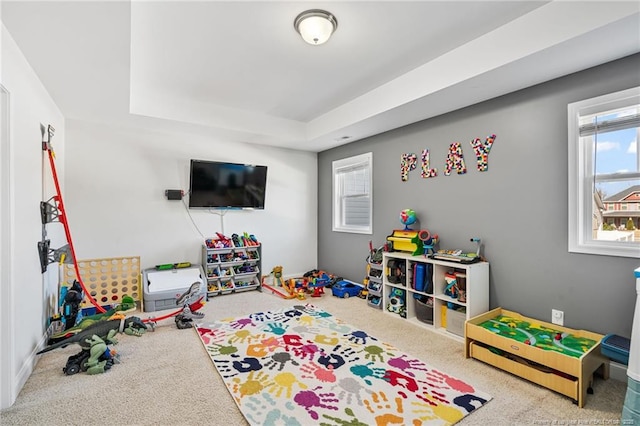 recreation room with carpet floors and a tray ceiling