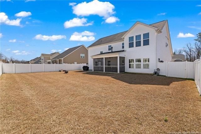 rear view of house with a gate, a lawn, a fenced backyard, and a sunroom