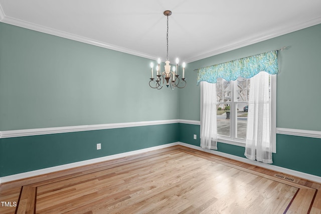 unfurnished room with an inviting chandelier, visible vents, wood finished floors, and ornamental molding