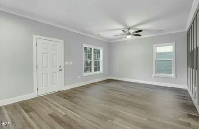 spare room featuring crown molding, baseboards, ceiling fan, and wood finished floors