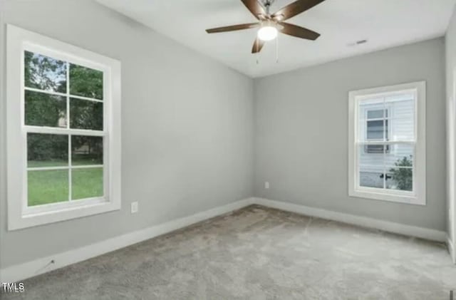 carpeted empty room with plenty of natural light, a ceiling fan, and baseboards