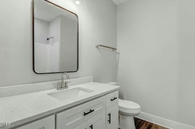 full bathroom with toilet, wood finished floors, vanity, baseboards, and walk in shower