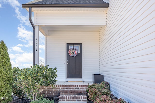 property entrance with roof with shingles and brick siding